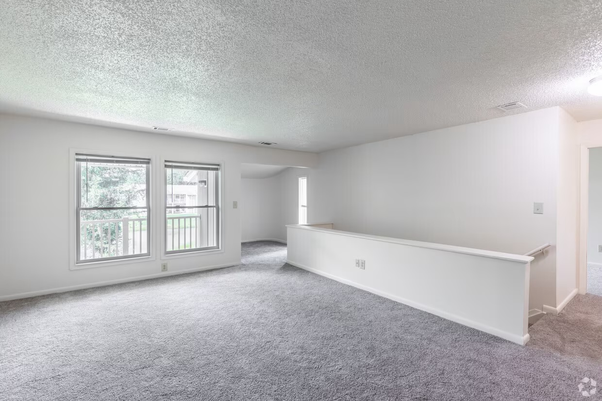Spacious carpeted living room in an Emerald Pond Estates one-bedroom apartment